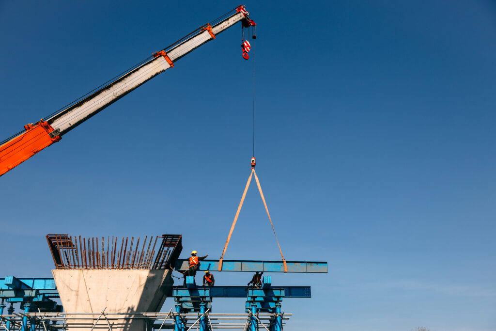 Grue soulevant un châssis en acier avec une élingue textile