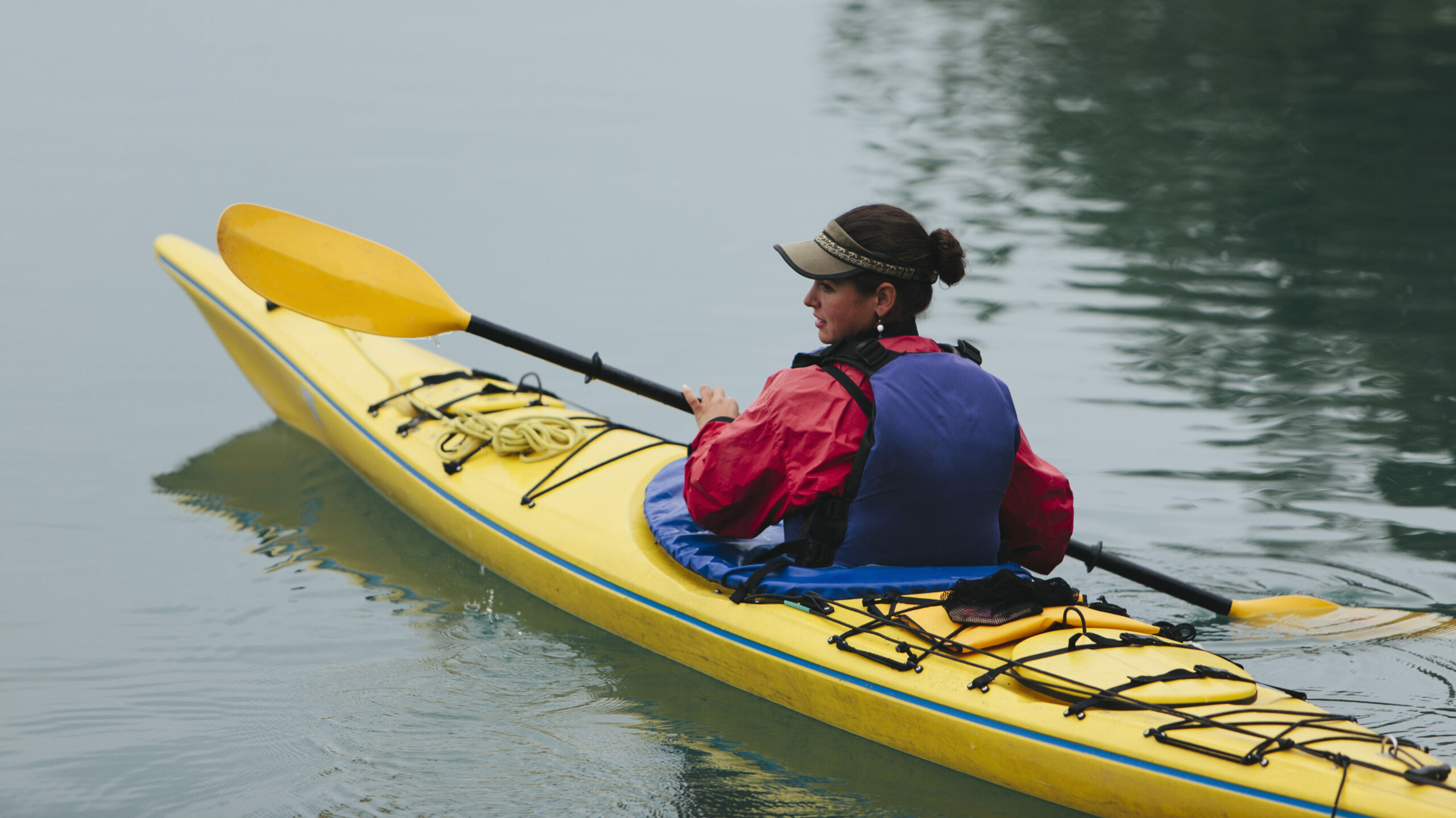 Une femme pratique le kayak et porte un gilet de flottaison