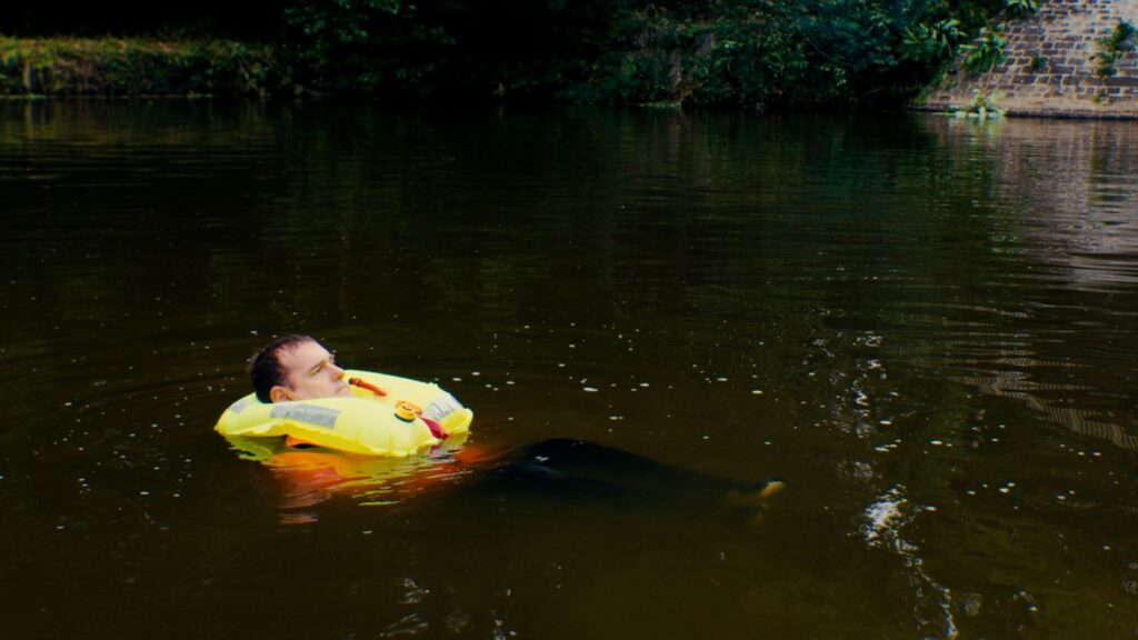 Personne flottant dans l’eau avec un gilet de sauvetage gonflable jaune maintenu autour du cou.