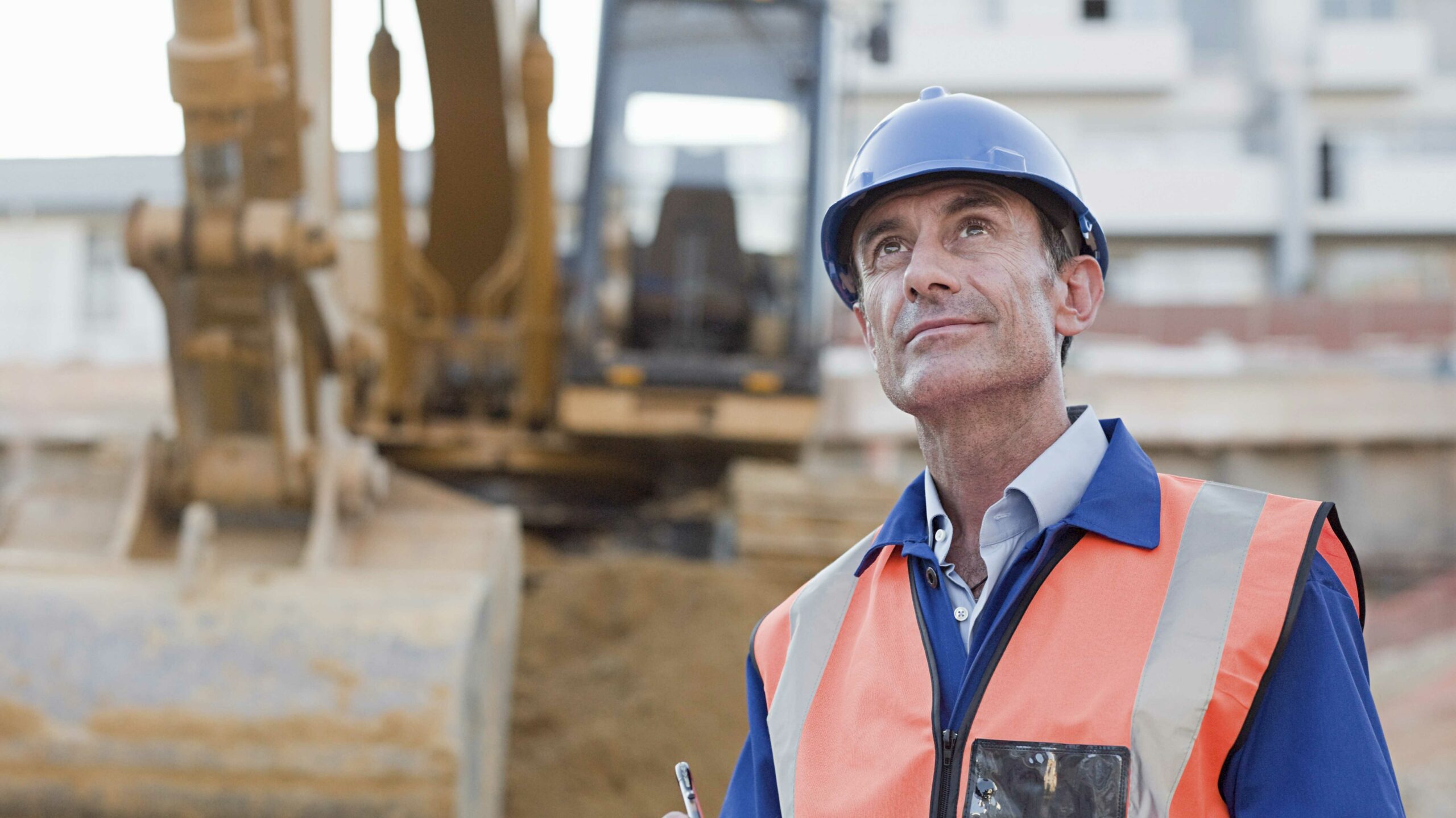 Professionnel équipé d’un casque et d’un gilet de sécurité contrôlant un engin de chantier dans le cadre d’une VGP.